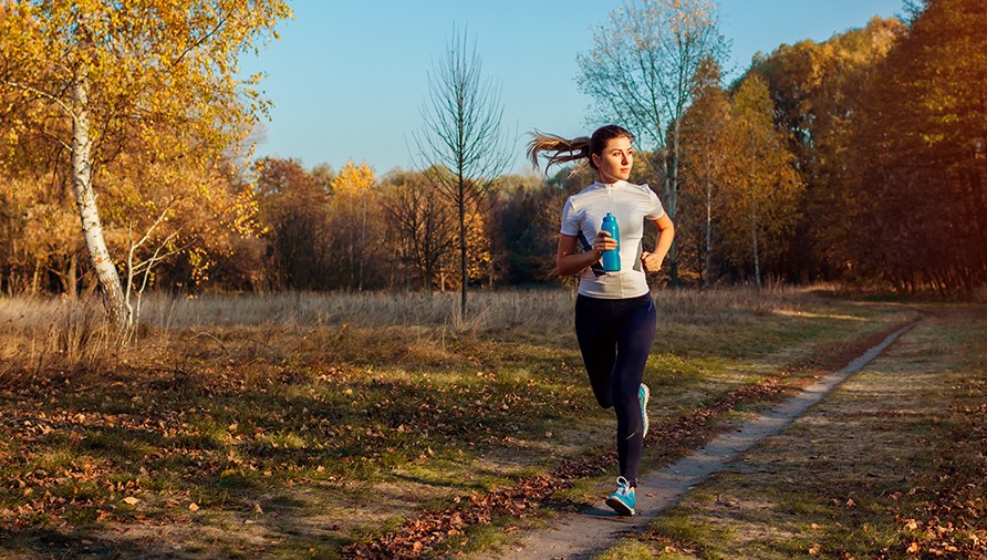 En kvinde løber ude i skoven om efteråret. En kvinde løber ude i skoven om efteråret.